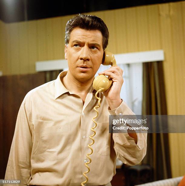 English actor and singer Max Bygraves pictured holding a telephone receiver in a scene from the television drama 'Sad About Eddie' in 1964.