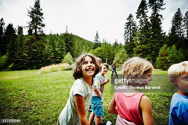 group of laughing kids standing in grass field - ferienlager stock-fotos und bilder