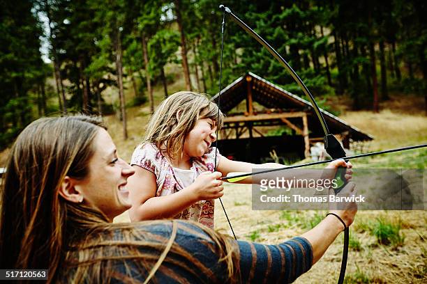 camp counselor helping young with bow and arrow - concentration camp photos photos et images de collection