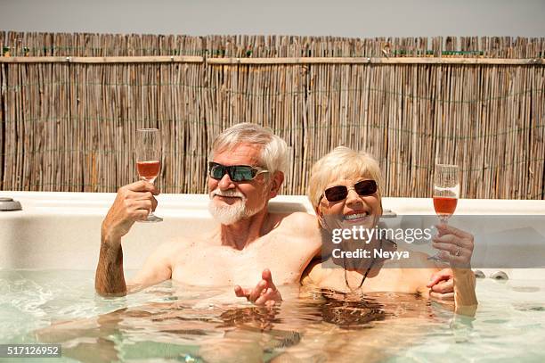 alegre pareja senior disfrutando de día de verano en el jacuzzi - balneario fotografías e imágenes de stock