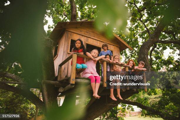 row of children sitting on a rustic wooden treehouse porch - tree house bildbanksfoton och bilder