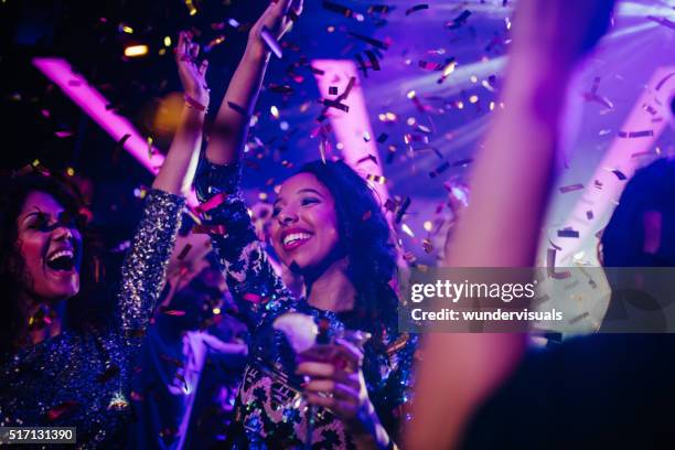 happy young friends partying with drinks and confetti in nightclub - girl dancing stock pictures, royalty-free photos & images