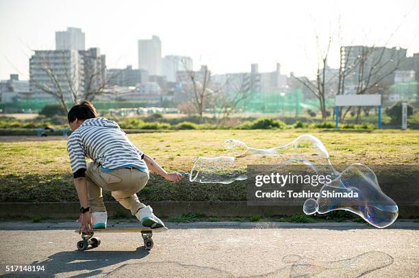 a man skateboarding with bubble soaping - initiative stock pictures, royalty-free photos & images