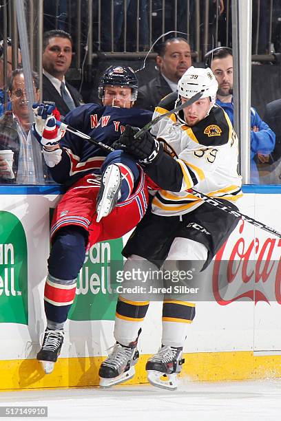 Matt Beleskey of the Boston Bruins throws a hit against Viktor Stalberg of the New York Rangers along the boards at Madison Square Garden on March...