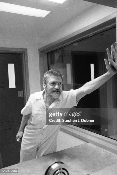 American domestic terrorist, luddite, and mathematics teacher Ted Kaczynski presses his hand against a reporter's through the dividing glass panel...