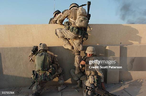 Marines of the 1st Light Armored Reconnaissance company, as part of 1st Battalion 3rd Marines, cross from one rooftop to another as they search...