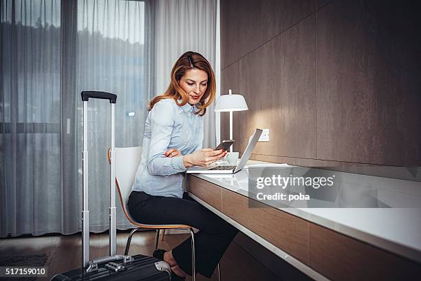 jovem mulher de negócios usando o celular no quarto de hotel - viagem de negócios - fotografias e filmes do acervo