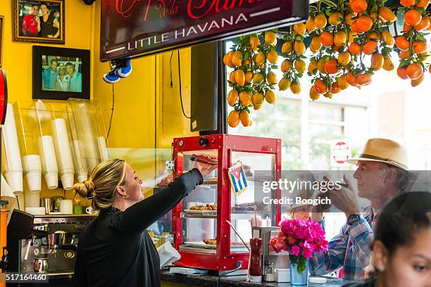 tourists buy cuban food from little havana cafe in miami - calle ocho carnival stock pictures, royalty-free photos & images