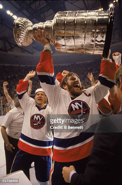 Canadian hockey player Denis Potvin, captain of the New York Islanders, holds the Stanley Cup in the air as the Islanders celebrate their first-ever...