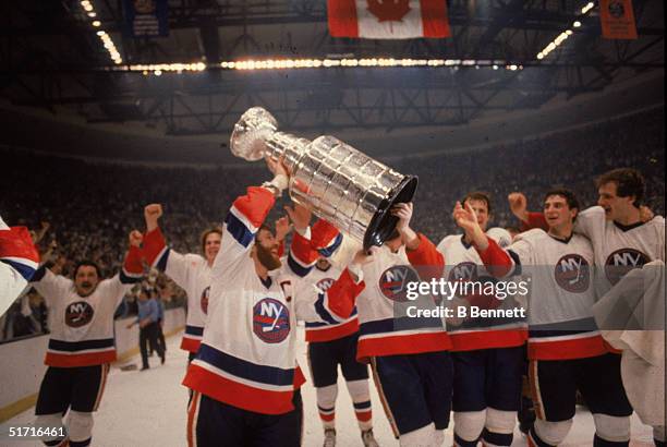 Canadian hockey player Denis Potvin , captain of the New York Islanders, and his teammates hoist the Stanley Cup in the air as the Islanders...