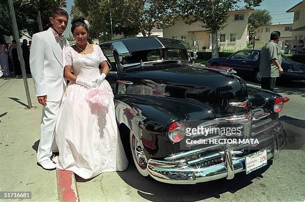 Delmy Roxana Figueroa and her best friend acting as "Chambelan de Honor" Roberto Carlos Herrera pose near an old Chevrolet as they exit the local...