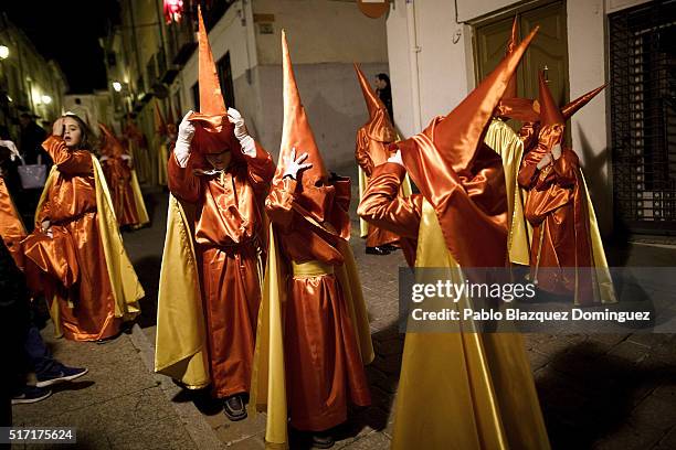 Young penitents from 'Santisimo Cristo de la Misericordia' brotherhood adjust their hoods at the end of a procession in the early hours on March 24,...