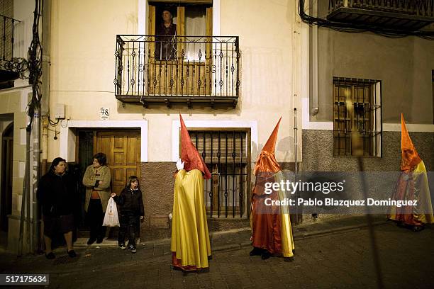 Penitents from 'Santisimo Cristo de la Misericordia' brotherhood walk the streets at the end of a procession in the early hours as members of the...