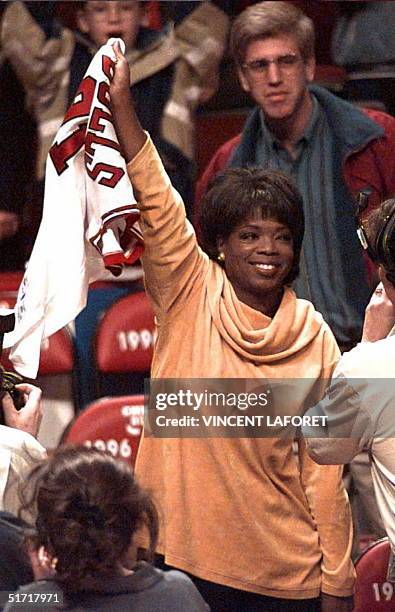 Talk show host and actress Oprah Winfrey waves Chicago Bulls forward Dennis Rodman's jersey after Rodman tossed her the jersey 07 May 1996 at the end...