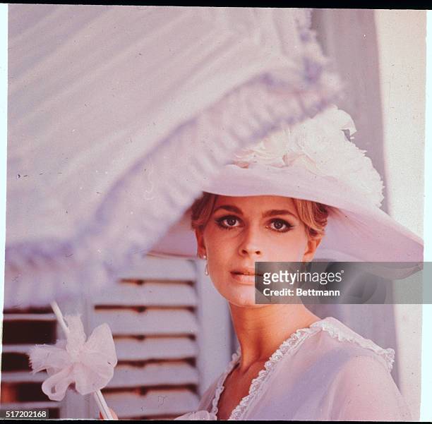Head and shoulders photo of actress/model Candice Bergen in a wide-brimmed white-feathered hat and a sheer white blouse.