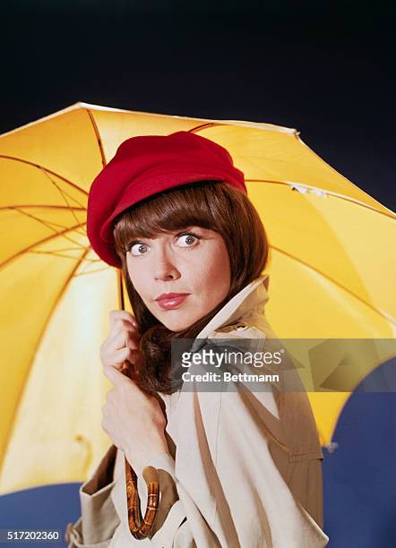 Publicity handout of Barbara Feldon in TV series Get Smart. Photo shows Barbara Feldon, wearing a raincoat and red hat, holding a yellow umbrella.