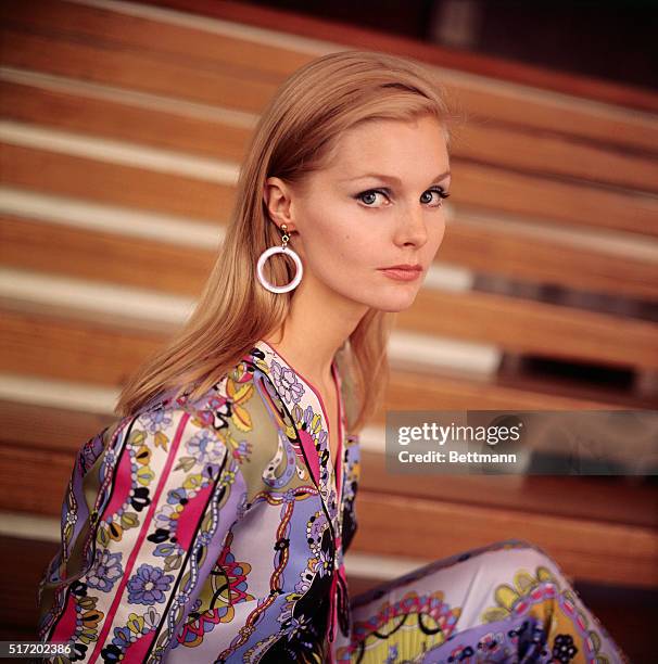 Portrait of actress Carol Lynley, wearing a brightly patterned outfit and hoop earings.