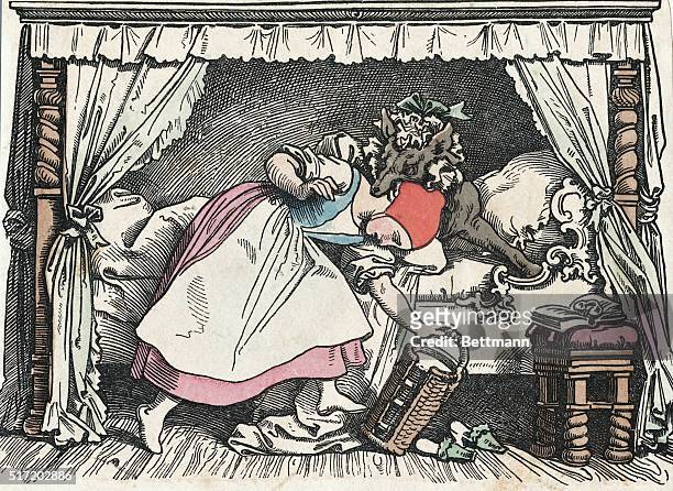 Illustration from a German retelling of "Little Red Riding Hood." In this scene, the Big Bag Wolf, disguised in bed as the grandmother, bites the...