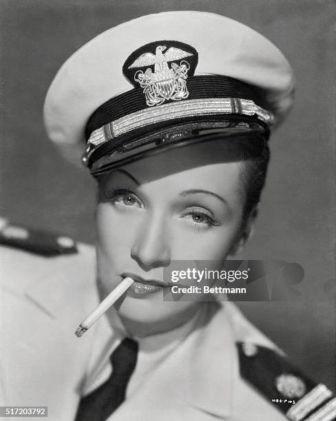 Marlene Dietrich wears the dress uniform of US Navy officer, while smoking.