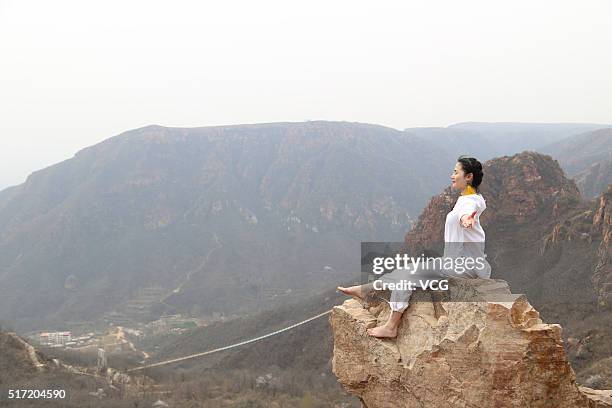 Woman does yoga on the precipice of Mount Song on March 23, 2016 in Zhengzhou, Henan Province of China. Over 10 yoga enthusiasts practice on the...