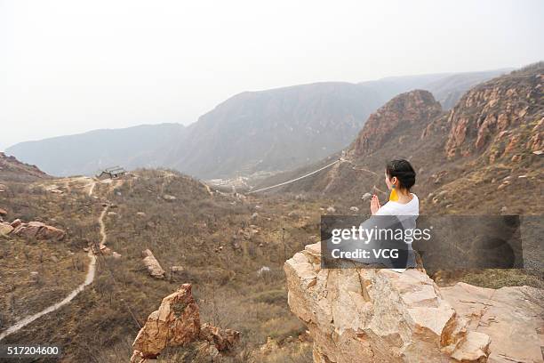 Woman does yoga on the precipice of Mount Song on March 23, 2016 in Zhengzhou, Henan Province of China. Over 10 yoga enthusiasts practice on the...