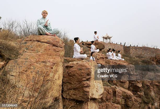 Women do yoga on the precipice of Mount Song on March 23, 2016 in Zhengzhou, Henan Province of China. Over 10 yoga enthusiasts practice on the...