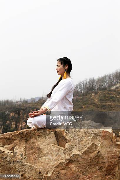 Woman does yoga on the precipice of Mount Song on March 23, 2016 in Zhengzhou, Henan Province of China. Over 10 yoga enthusiasts practice on the...