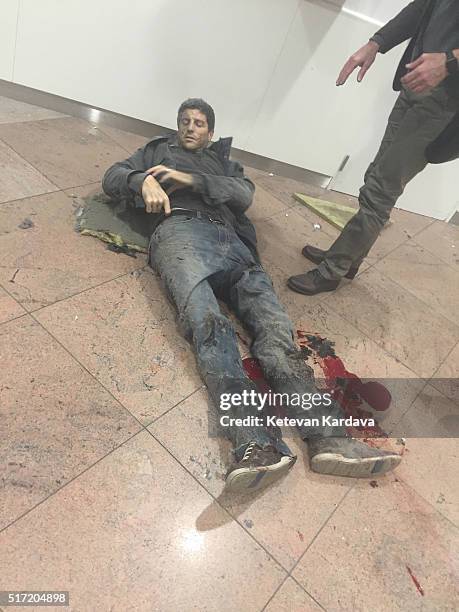 An injured man lies amongst debris following a suicide bombing at Brussels Zaventem airport on March 22, 2016 in Brussels, Belgium. Georgian...