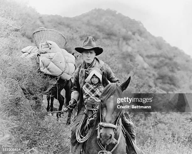 American actor and director William S. Hart as Jefferson "Riddle" Gawne, and Mary Jane Irving as the young Jane Gawne, in a scene from the silent...