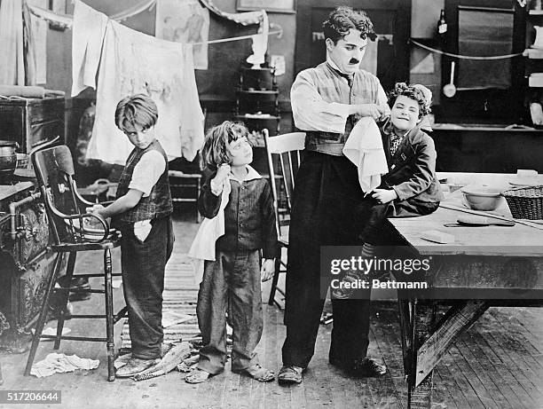 Charlie Chaplin on the set with three small children in a scene eventually cut from his 1918 film 'Shoulder Arms'. From left to right, the children...