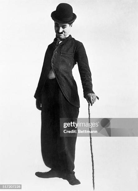 Full length shot of Charlie Chaplin in typical pose and attire--long-tailed coat, baggy trousers, bowler hat slightly cocked, bambu cane. Undated...