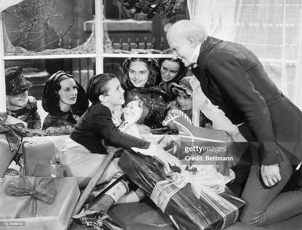 Scrooge Watching Tiny Tim Open Gifts
