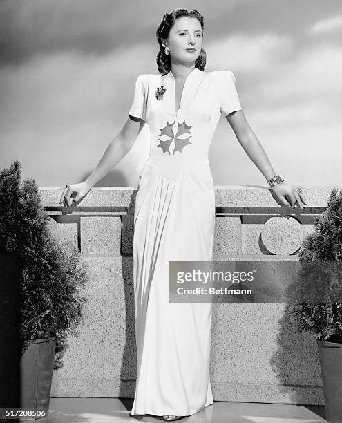 From her personal wardrobe, Barbara Stanwyck, who appears in the Warner Brothers film, "My Reputation," models a chalky white dinner gown styled with...