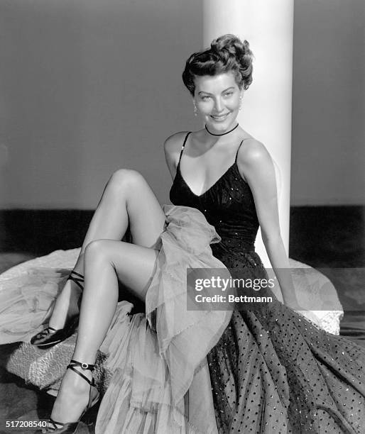 Picture shows sctress, Ava Gardner, posing in a sleeveless, chiffon dress with her legs exposed. Undated photo circa 1950s.