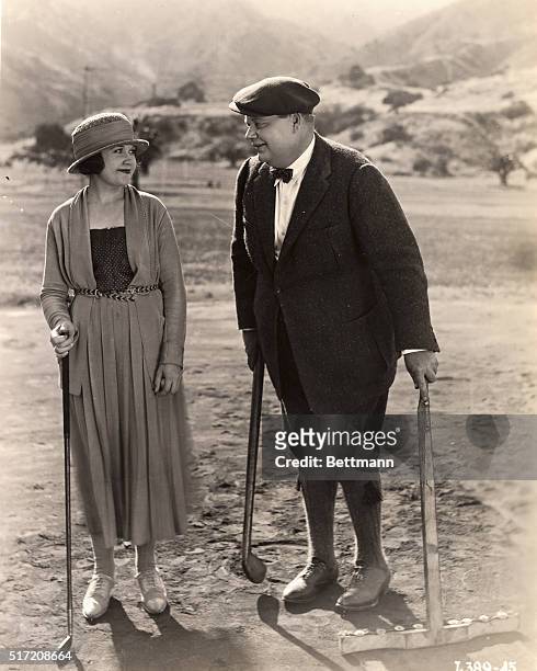 Silent movie scene featuring Roscoe "Fatty" Arbuckle and Mabel Normand sharing a happy moment on a golf course.