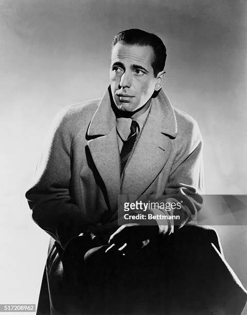 Publicity handout of actor Humphrey Bogart wearing his coat collar raised, 3/4 length, ca. 1930s.