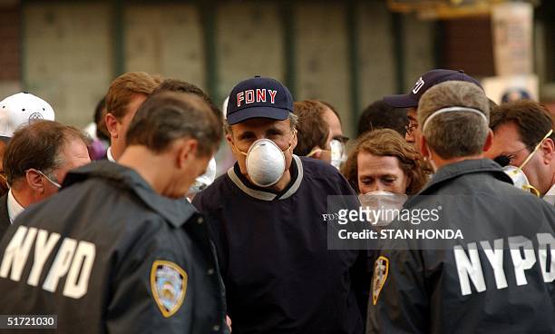 New York Mayor Rudolph Giuliani wears a dust mask after a tour of the damage in Lower Manhattan 12 September 2001 in New York one day after a...