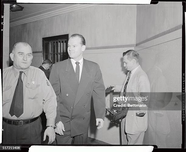 Dr. Samuel Sheppard, handcuffed to a deputy, smiles as he is led from jail cell to court December 30th where attorney William J. Corrigan, in an...