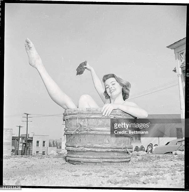 Myrna Hansen, "Miss U.S.A." in the Miss Universe contest, fits comfortably in a wooden tub near the set of Man Without a Star and proceeds to refresh...