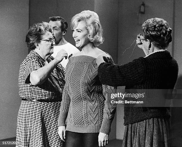 Two costumers attend to a laughing Marilyn Monroe as she prepares to rehearse a dance routine for the film Let's Make Love. Choreographer Jack Cole...