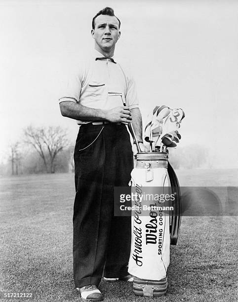 Pro-golfer Arnold Palmer posing beside golf bag and clubs in advertisement for Wilson Sporting Goods Company.