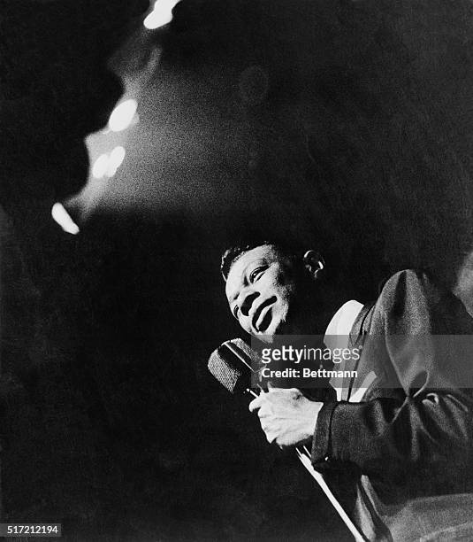 Singer Nat "King" Cole holding microphone during a concert.