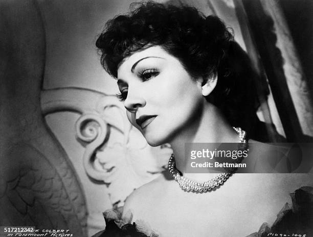 Closeup side view portrait of the beautiful Paramount Picture actress, Claudette Colbert. Head and shoulder photo with her head leaning against a...