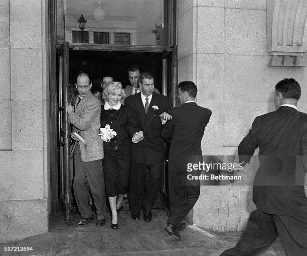 San Francisco, CA: "Mr and Mrs." Film star Marilyn Monroe and former Yankee great Joe Di Maggio press through a crowd of newsmen after their marriage...
