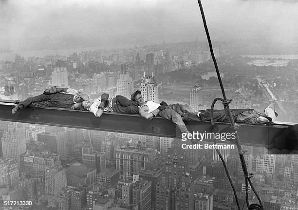 Four construction workers take a nap, balanced on a steel girder hung 800 feet over Manhattan, during the construction of the RCA Building. Man on...