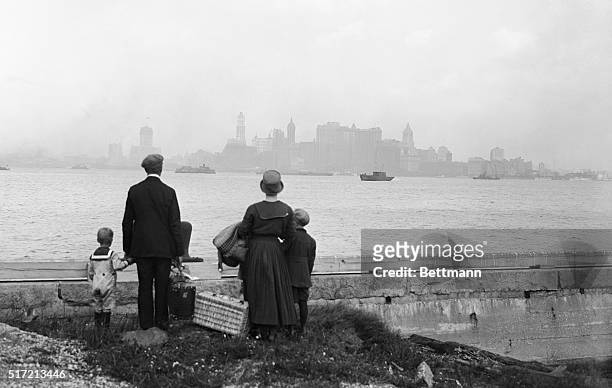 New York, NY: Above is a striking photo showing a little immigrant family on the dock at Ellis Island, N.Y., just having passed the rigid examination...