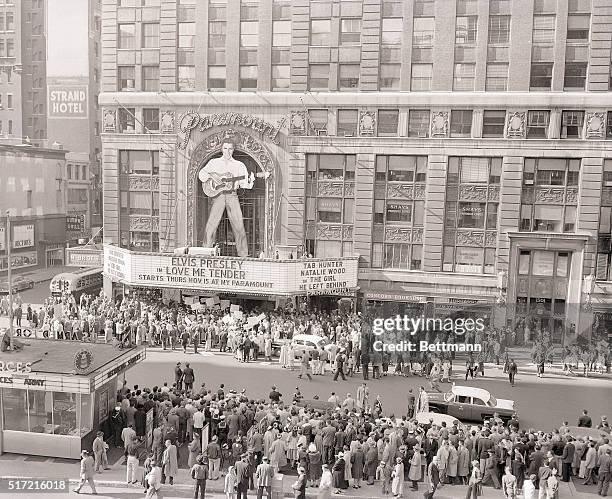 Droves of fans and curious Sunday afternoon strollers crowd outside the Paramount Theater where a 40-foot figure of rock 'n' roll idol Elvis Presley...