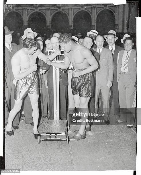 Friendly Enemies at Traditional Weigh-In. New York: Both looking serious, Joe Louis and Max Schmeling, principals in the fight of the century shake...