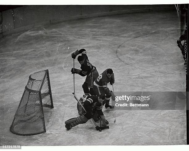 Goalie Jim Henry of the New York Rangers shuffles the puck away from his net to thwart a scoring attempt by Pat Mcreavy, , of the Detroit Red Wings...