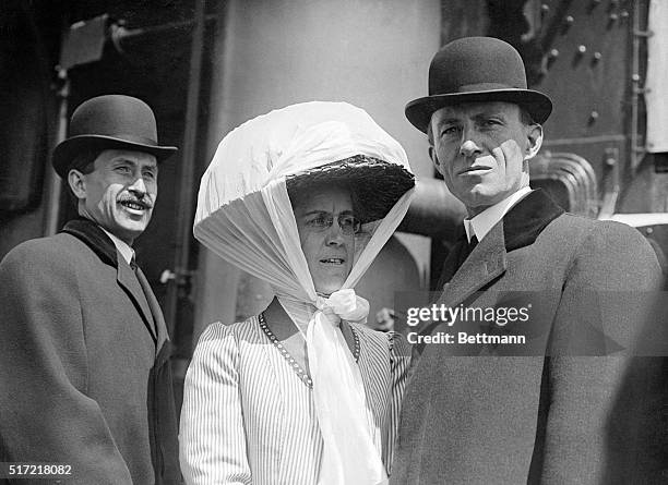 Inventors Orville and Wilbur Wright stand with their sister Katharine on the deck of a ship.